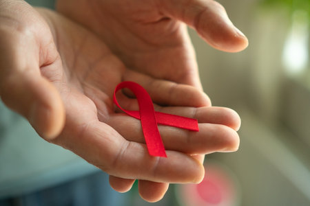 Male hands carefully holding red awareness ribbon, representing solidarity with HIV positive people...