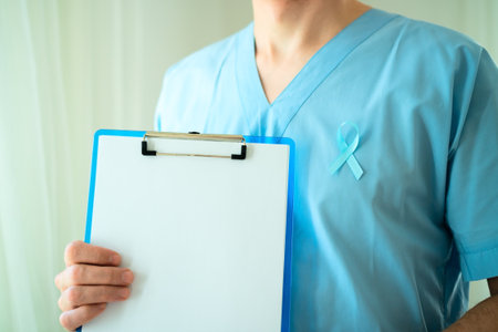 Male healthcare professional in uniform with blue ribbon symbol of prostate cancer awareness holding clipboard with empty paper for notes and reminders in November.の写真素材