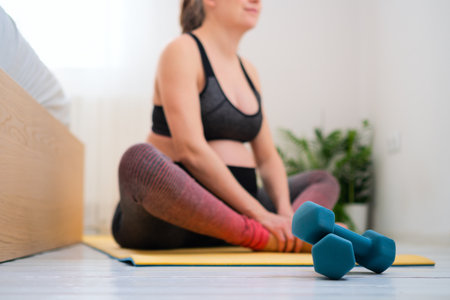 Dumbbells in the foreground, pregnant woman gently stretching behind. Daily health practice.の写真素材
