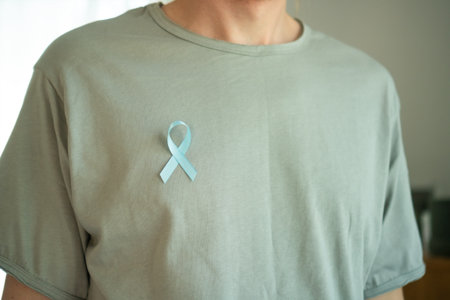 Close up of a man with a blue satin ribbon pinned on his shirt. Symbol of November prostate cancer...
