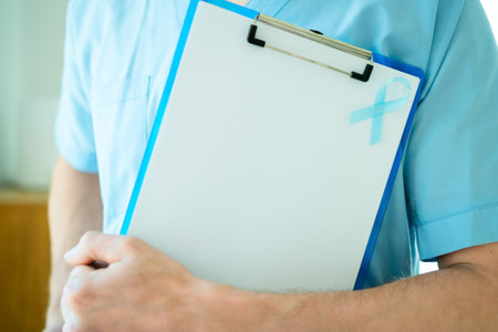 Close up of a young nurse or medical staff man with blue ribbon attached to clipboard. Symbol of prostate cancer awareness and early detection during November health month.の写真素材