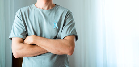 Man with blue ribbon on shirt, arms crossed. Symbol of November prostate cancer awareness, medical diagnosis, early detection, and emotional support for oncology patients. Horizontal Bannerの写真素材