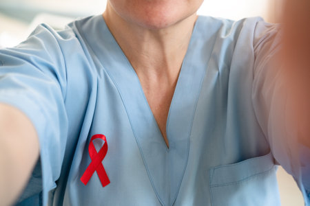Woman medical professional taking phone selfie with red ribbon on uniform, showing support and...