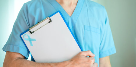 Medical worker man in uniform holding blank document with blue ribbon. Prostate cancer awareness symbol in November, early diagnosis, prevention, and medical support concept.の写真素材