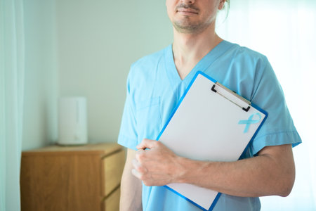 Close up of a young nurse or medical staff man with blue ribbon attached to clipboard. Symbol of prostate cancer awareness and early detection during November health month.の写真素材