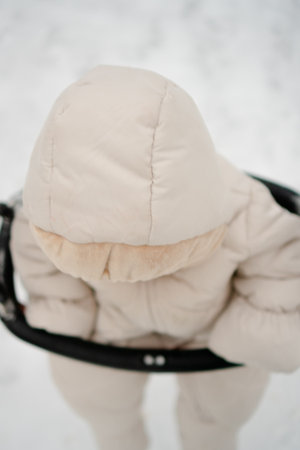 An adorable toddler, dressed in a warm snowsuit, enjoying a winter swing. The cozy outfit and curious expression highlight the joy of outdoor play for a baby, child, or newborn in snowy weather.の写真素材