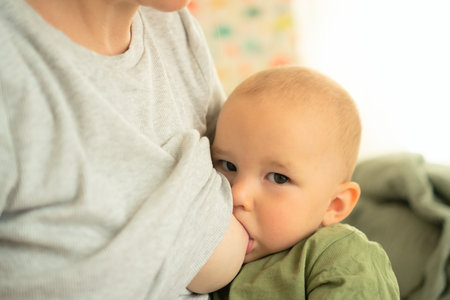 Content baby receiving mothers milk while sitting in loving arms. Intimate portrait of natural weaning and nutritional breastfeeding moment.の写真素材