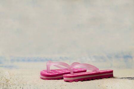 pair of pink flip flops in the sand