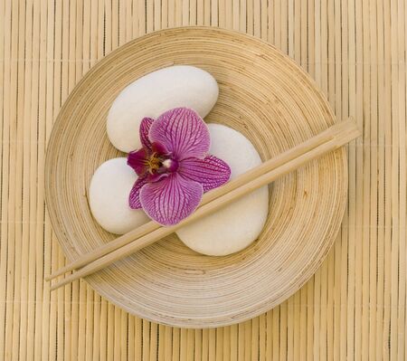 still life with pink orchid flower and white pebble on bamboo plateの写真素材