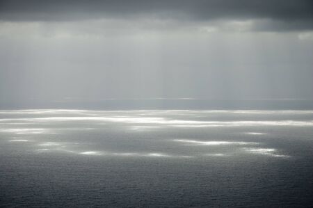 gray clouds and sunshine over gray sea at Canary Islandsの写真素材