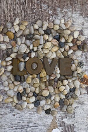Word Love in rusty letters on pebble and driftwood backgroundの写真素材