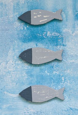 three wooden fish on blue backgroundの写真素材