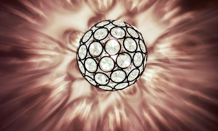 bright lighting ball with circle patern hanging from the ceiling on the ivory ceiling with light reflection, abstract reflection on ceiling from luxury light ball chandelierの写真素材