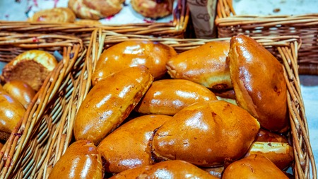Many fresh beautiful patty in shop square wicker basket wait for first morning buyers. Pattys as perfect sweet breakfast. Freshly baked sweet buns or bread rolls, closeupの写真素材