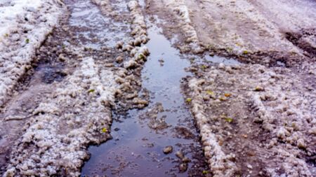 spring weater in a winter day with sun heats the snow at the road. many water and dirty snow as spring background. Dirty melting snow with wheels trailsの写真素材
