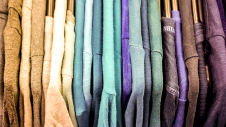 many colorful bright clothes on hangers before sale season in big market. Clothing rack with dark hangers and bright clothes.の写真素材