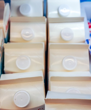 strong rows of milk in white carton packaging with round cap on the top stay at store shelf top side view. fresh organic milk wait for buyers in shopの写真素材