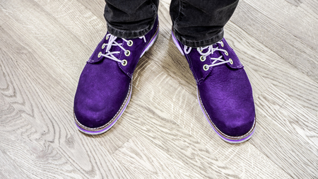 Bright violet boots with ivory shoelace on mens legs with big size against light ivory wooden floor. Close up view on man's legs in black jeans and brown leather boots. Toned picture.の写真素材