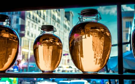 three different round bottles with peach transparent liquid stand on wooden shalved against big window with street in small family restaurant, fruit compote bottled and placed as a decorationの写真素材