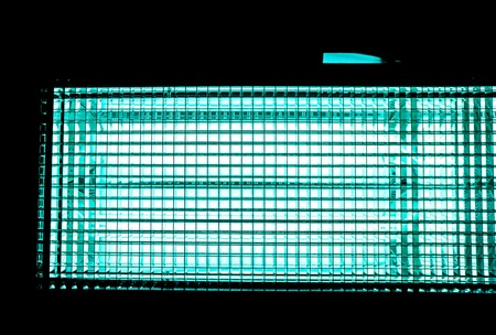 toned to blue turquoise metal mesh with a square pattern on a bright lamp with gradient effect on a black background, close-up of movie illuminant against black backgroundの写真素材