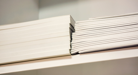two strong rows of new thin books with white paper one is higher then another one lay on white...