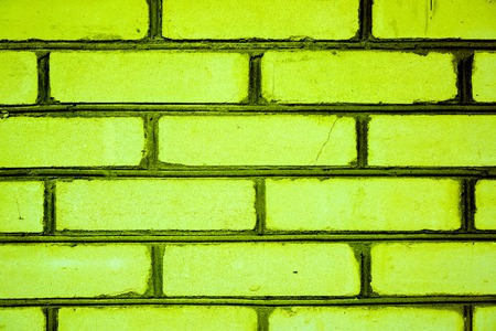 bright juicy green bricks as part of wall or fence with dark lines between bricks with some cracked parts. Colored brick background. Colorful brick wall pattern, painted bricks as urban textureの写真素材