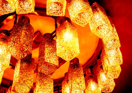 round part of golden yellow orange decorative modern shaped lamps on ceiling against dark background, many modern ceiling lamps with abstract ornament as luxury chandelierの写真素材