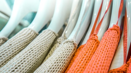 ivory and coral orange raglans with a large pattern knit on white shopping similar racks on clothes shop. bright different clothes on the rack before sale season. new collection in clothes luxury shopの写真素材