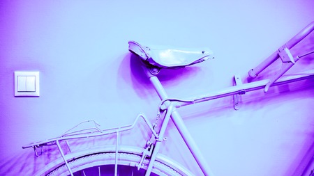 lilian pink violet color saddle with part of frame and wheel as part of old painted bicycle used for decoration in office. vintage bicycle on decorative color wallの写真素材