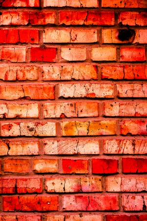 vintage wall with many small orange red coral carrot broken bricks on very old brickwall with dark lines between bricks as background. Colorful brick wall pattern, painted bricks as urban textureの写真素材