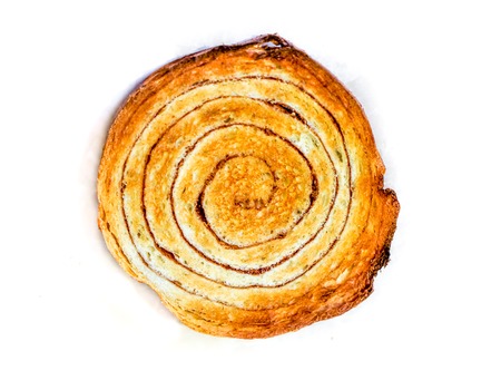 big sweet round cinnamon bun with dark spiral and texture of a porous dough inside with dark brown crispy crust. bun as sweet fresh snail on white backgroundの写真素材