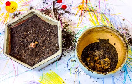 two flower spots one round and empty and another hexagon form and with grey dry ground inside...