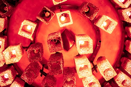 fire yellow orange decorative modern shaped lamps on ceiling against dark background, many modern ceiling lamps with abstract ornament as luxury chandelierの写真素材