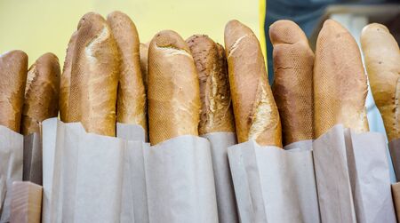 Fresh baked rustic bread loaves in paper bags on market shelfの写真素材