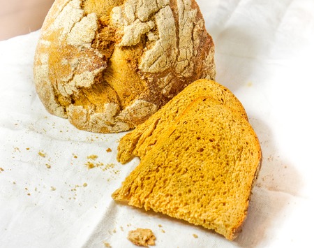 two cutting peaces of dark bread with fried crust lay one on one near quarter of a loaf of bread...