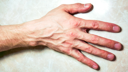 hand lay horizontal on table. right hand with five fingers and neat flat nails on the back of his hand up. successful businessman lay his hand on tableの写真素材