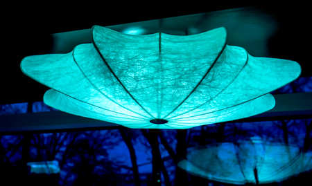 bright blue chandelier with light inside as umbrella against black background. umbrella lamp hangs his cane up as decoration of modern night club. Lighting umbrella shape from small lamps at nightの写真素材