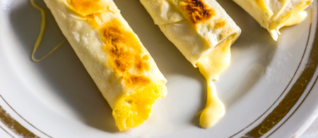 white plate with golden ornament with three peaces of thin Armenian bread lavash fried with crispy crust. lavash sandwich with cheese folded in an envelope with cheese drop as light hot breakfastの写真素材