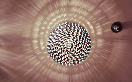 many small crystal lamps on ball with lines patern hanging from the ceiling on the ivory ceiling with light reflection, abstract reflection on ceiling from luxury light ball chandelierの写真素材