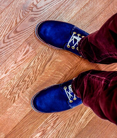 man's legs as horizontal lines top view. Close up view on man's legs in burgundy jeans and dark blue...