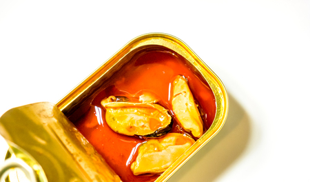 small square brilliant can with three orange mussels that swimming in orange golden oil against white background. Food Still Life with seafood delicacies. marinated in oil mussels in a canの写真素材