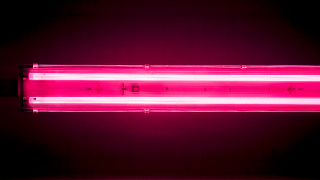 two bright horizontal lamps. pink lilian crimson horizontal lamp on black ceiling, long lamp divided into sections with lights and gradient effect against dark office ceiling, abstract background with lightning linesの写真素材