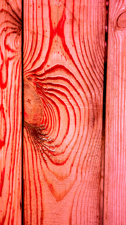 close up of coral red wooden planks with round knots and lines around them as waves on sea. abstract lines on wood as natural background. natural wooden texture of fence, wall or floor as backgroundの写真素材
