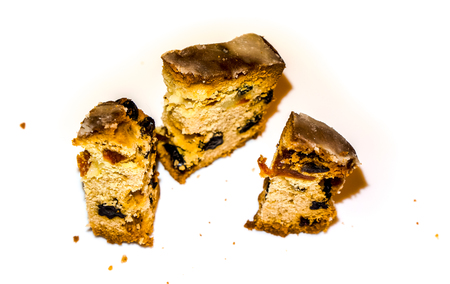 isolate three small peaces of holiday cake with raisins and other dried fruits surrounded by crumbs against white background. Christmas Stollen on a white plateの写真素材