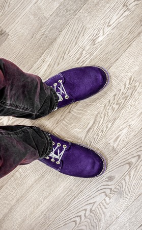 dark violet boots with ivory shoelace on mens legs with big size against light ivory wooden floor. Close up view on man's legs in black jeans and brown leather boots. Toned picture.の写真素材