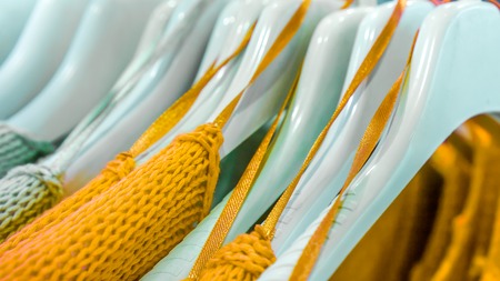 orange raglans with a large pattern knit on white shopping similar racks on clothes shop. bright different clothes on the rack before sale season. new collection in clothes luxury shopの写真素材