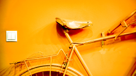 white socket near bright bronze coral part of wheel, part of frame and saddle as part of old painted bicycle used for decoration in office. vintage bicycle on decorative color wall in art officeの写真素材