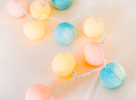 blue ivory yellow coral knitted light ball with light inside laying on the ivory background. colorful Ball party lamp on the ground as part of prepearing for the party. decorative light ballsの写真素材