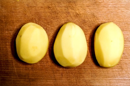 few cutting raw peeled potatoes against old wooden background. top view to potatoe circles. raw food backgroundの写真素材