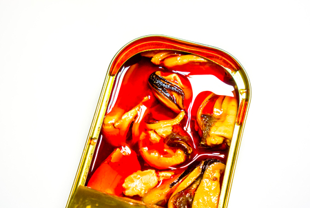close-up of open metal can with delicacy. marinated square brilliant can with three orange mussels that swimming in orange golden oil against white background. Food Still Life with seafood delicaciesの写真素材